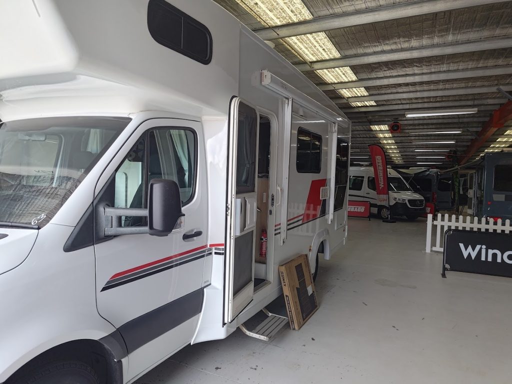 Side view of the Mercedes Sprinter KEA motorhome at the dealership, showing the entry door and original exterior layout before upgrades.